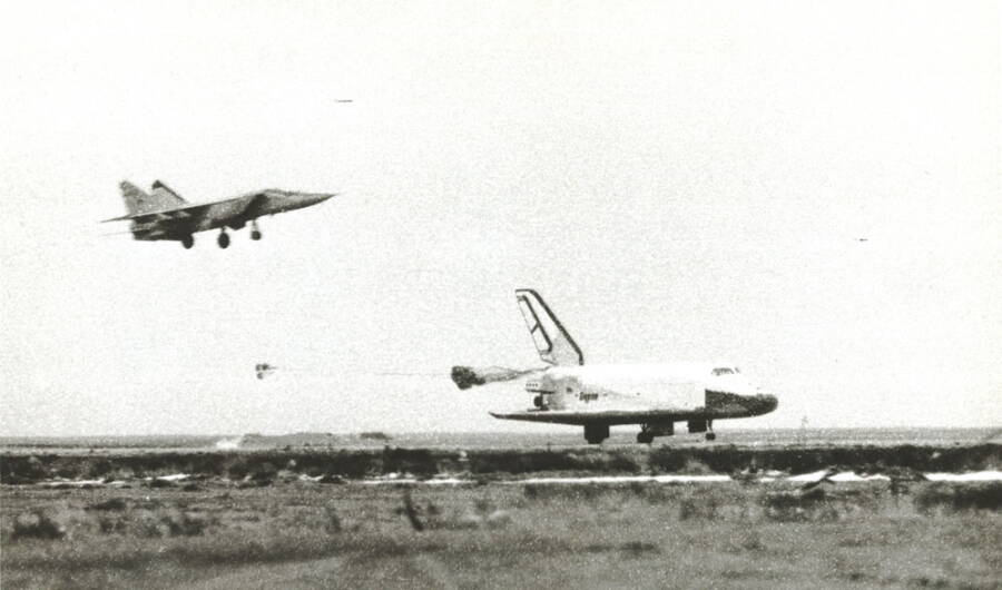 Космический корабль «Буран» выпускает тормозные парашюты во время посадки, 15 ноября 1988 года. Над ним – истребитель МиГ-25, контролировавший взлет и посадку корабля