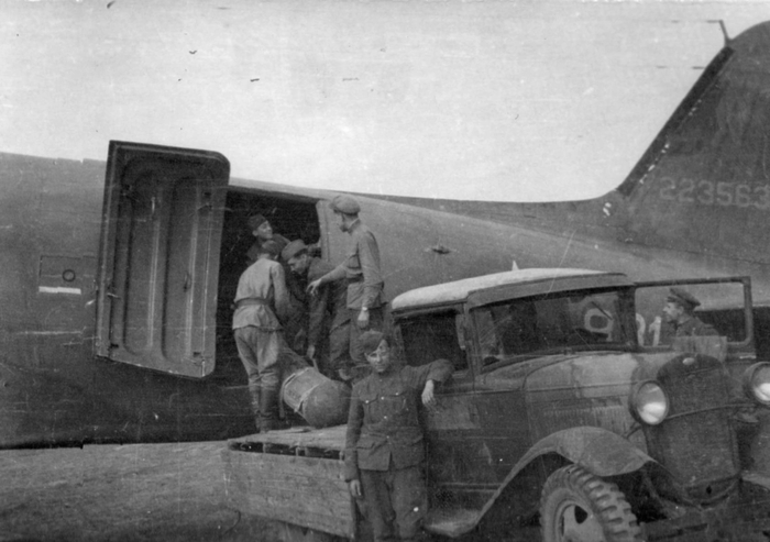 Советские солдаты укладывают в транспортный самолет DC-3 грузы для партизан на Украине из кузова грузовика ГАЗ-АА