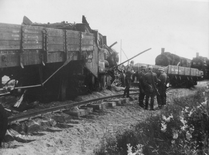 Немецкие солдаты возле поезда, подорванного советскими партизанами. Железнодорожная платформа, прицепленная перед паровозом, не помогла избежать подрыва, паровоз полностью сошел с рельсов