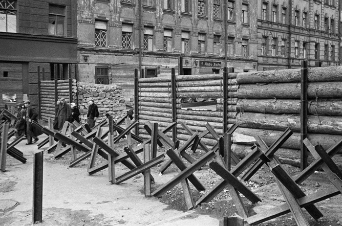 Мирные жители проходят мимо баррикады на выезде из Ленинграда